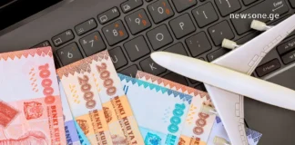 ეკონომიკა ციფრულ ეპოქაში – როგორ ვაქციოთ დანაზოგი გამოცდილებად? A toy airplane and banknotes on a laptop keyboard representing global economy and travel budgeting.