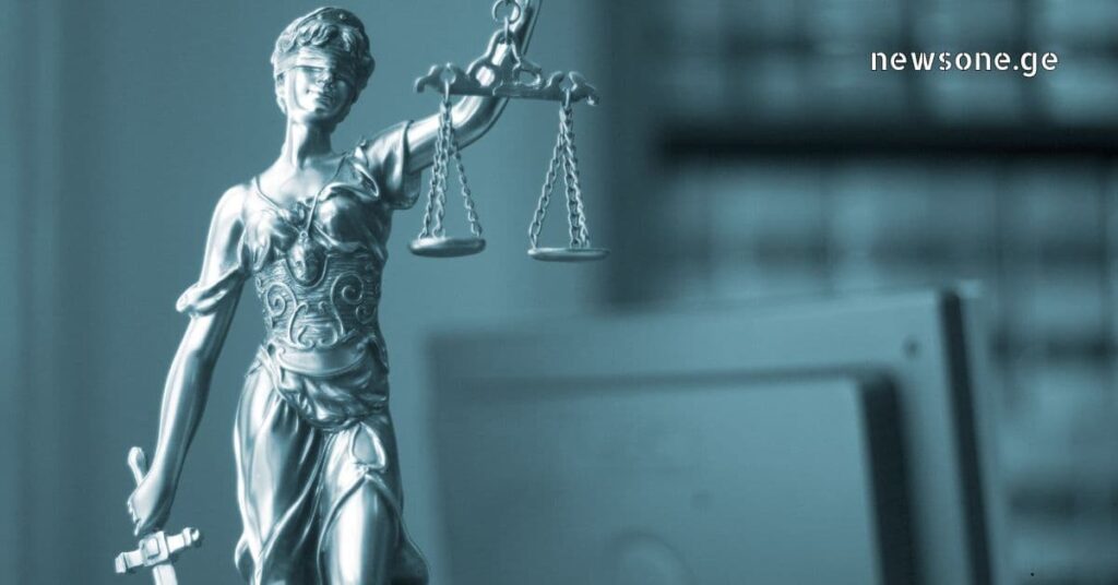 A silver statue of Lady Justice (Themis) holding scales and a sword, symbolizing law and justice, with a blurred office background.